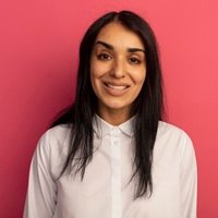 smiling young beautiful girl looking at camera wearing white t-shirt isolated on pink background